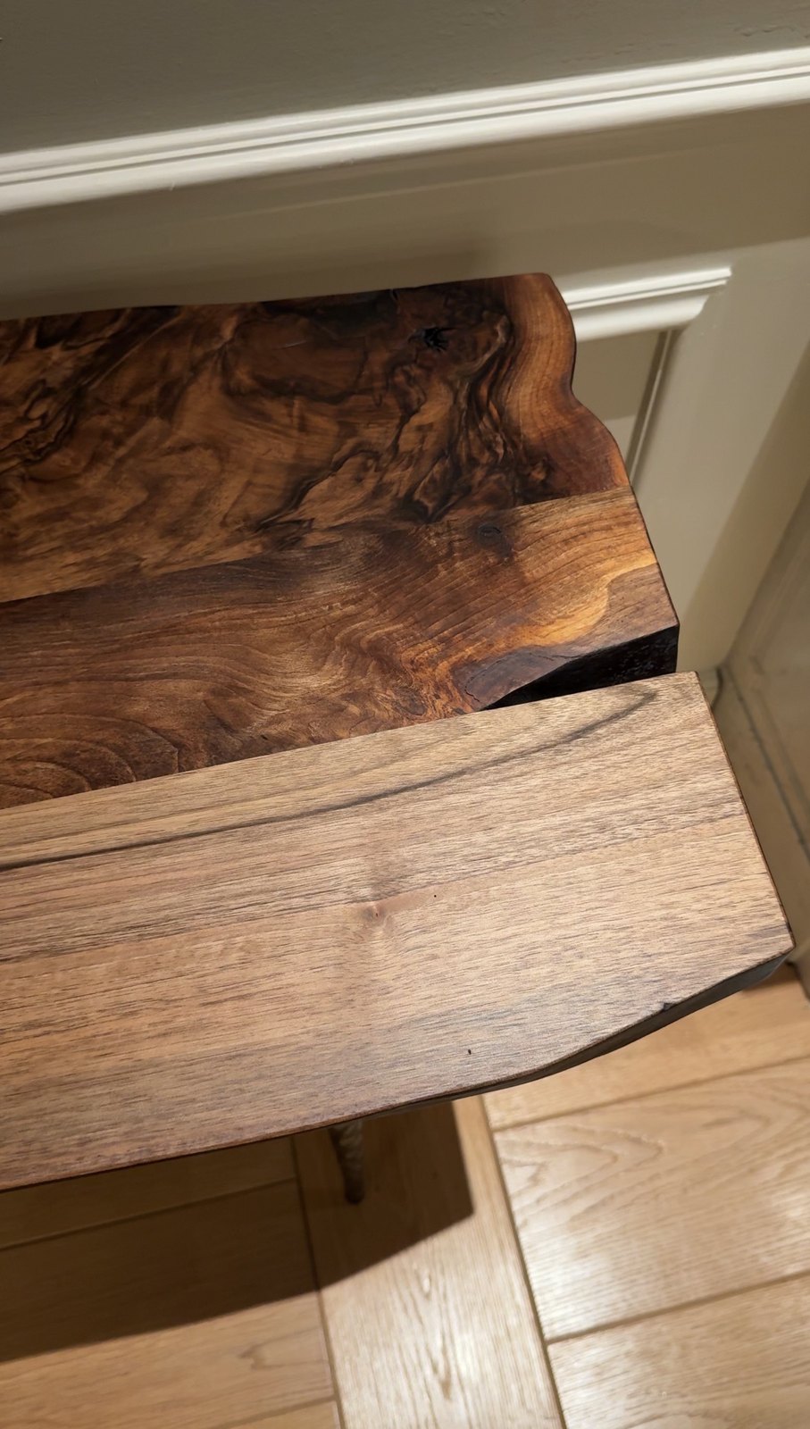 A live-edge walnut table, its surface a dense swirl of burl figure.
